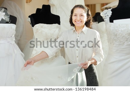 Mature woman shows bridal dress at wedding store