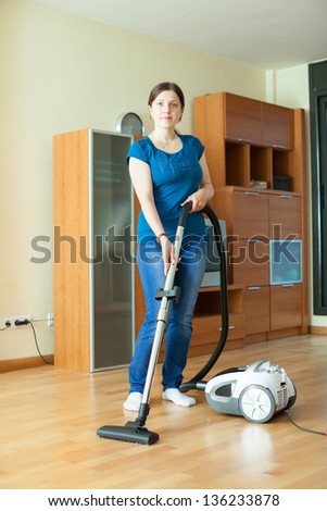 full length shot of girl cleans with vacuum cleaner at home