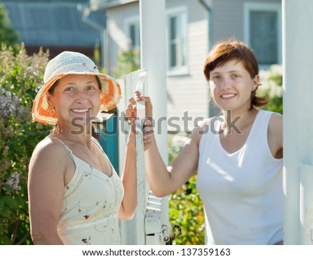 Two happy women near fence wicket. Selective focus on left woman