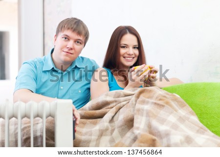 Couple  relaxing at home near oil heater