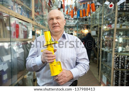 mature man holds  shock absorber  in  auto parts store