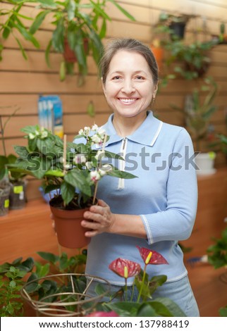 Happy  woman with Clerodendrum surrounded by different flowers in flower store