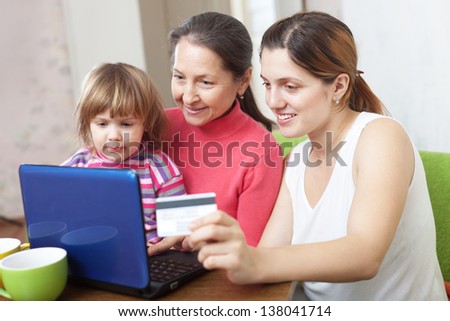 Happy family of three generations with laptop, paying by credit card in internet store