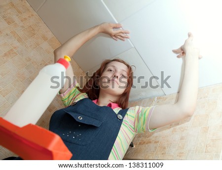 Woman glues ceiling tile at home