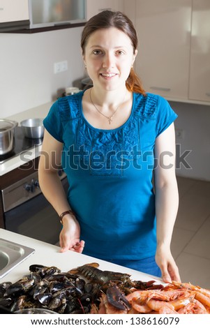 Young housewife with raw seafood  in home kitchen