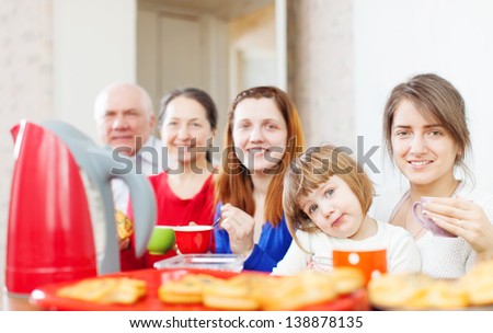 family drinks tea and eats cakes at home