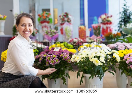 Happy mature woman with chrysanthemum at flower store