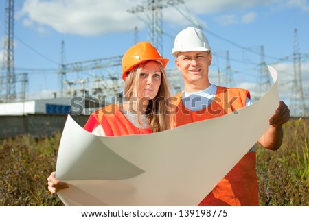 two workers wearing protective helmet works at electric power plant
