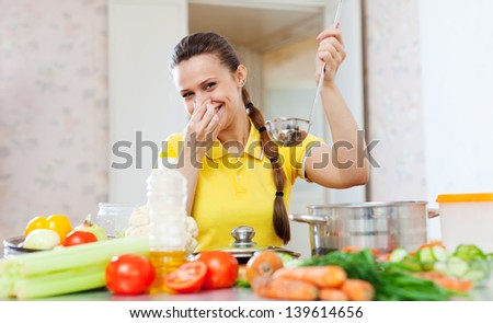 young woman holding her nose because of bad smell from food at kitchen
