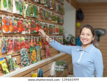 Smiling mature woman chooses the seeds at store for gardener