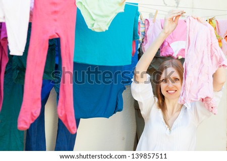Positive long-haired girl drying clothes on clothes-line