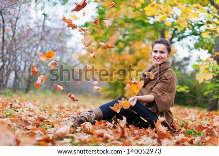woman throws autumn leaves in the park