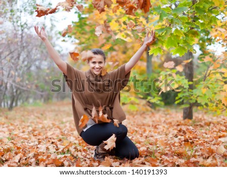 Woman throws autumn leaves in the park