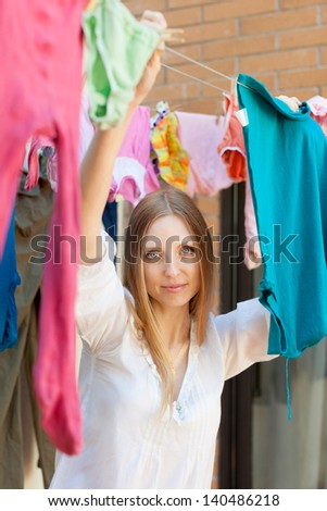woman hanging clothes to dry on clothes-line after laundry