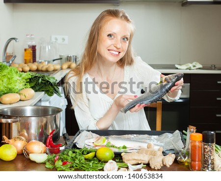 woman putting  saltwater fish into sheet pan at kitchen