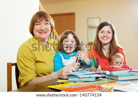 Portrait of senior woman with daughter and grandchildren drawing on paper at home. Focus on mature