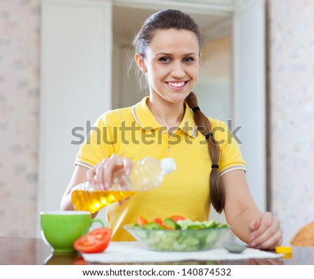 European woman  pouring oil from bottle into plate with veggie salad
