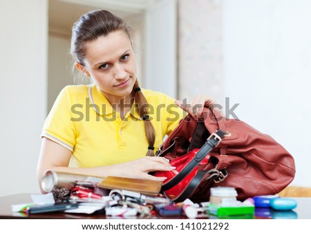 beautiful woman can not finding anything in her handbag at table