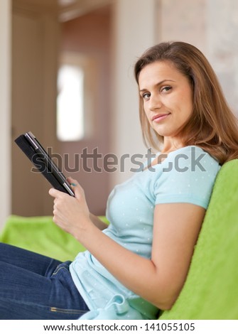 Young woman reads e-reader on sofa at home