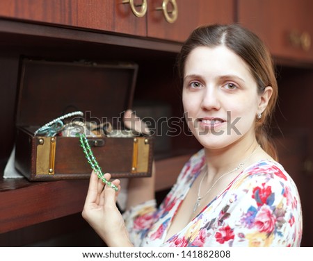portrait of  woman with jewelry in treasure chest at home interior