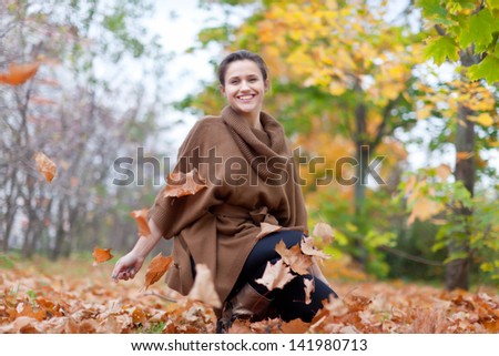 Girl throws maple leaves in autumn park