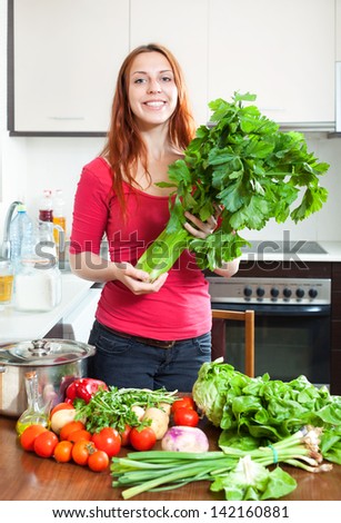 Portrait of happy  woman  with  fresh  vegetables and greens at home