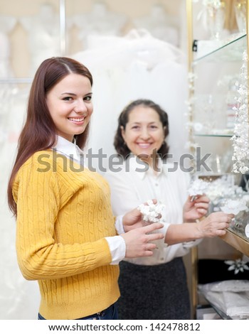 bride chooses bridal accessories at wedding store. Consultant helps her