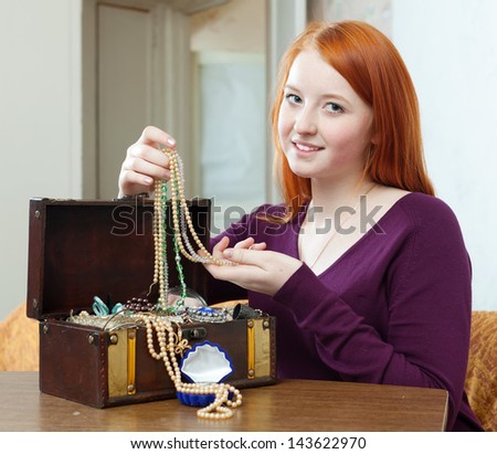 teenager girl looks jewelry in treasure chest at home