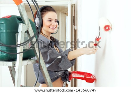 Happy girl with roller makes repairs at home