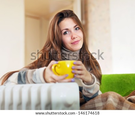 woman  with yellow cup near oil heater at home