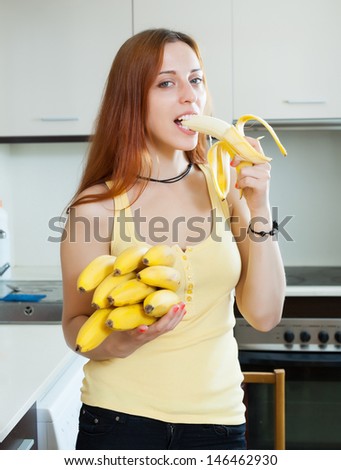 long-haired woman eating banana at home kitchen