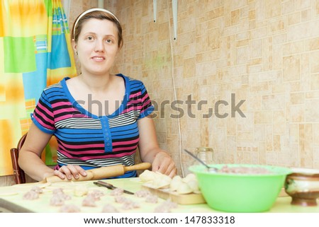 Woman making russian meat dumplings (pelmeni) in her kitchen