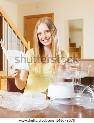 Happy blonde woman reading user manual for new electric steamer at home