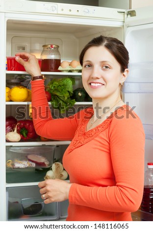 Young woman looking for something in refrigerator  at home