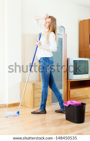 long-haired girl washing parquet floor with mop at home