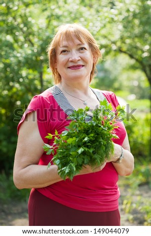 Mature woman with harvested dill and parsley  in garden