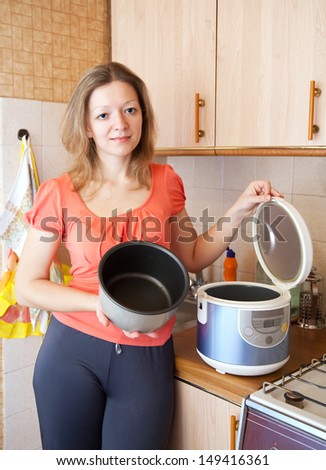 Young woman with slow cooker in her kitchen