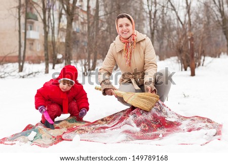 mother with daughter cleans carpet with snow