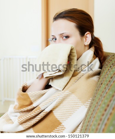 sick woman in plaid uses handkerchief in home