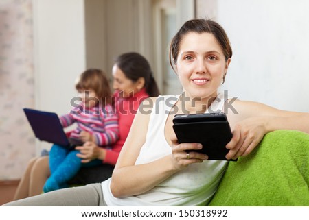 Family of three generations on sofa in livingroom  with electronic devices