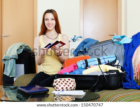 Young woman packing documents into suitcases going on holiday
