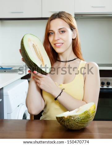 long-haired woman holding melon in home kitchen