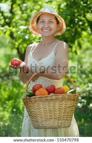 mature woman with basket of harvested vegetables