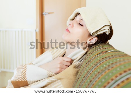 sick young woman uses handkerchief on her head in home