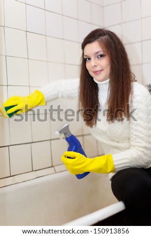 woman cleans bathroom with sponge at her home