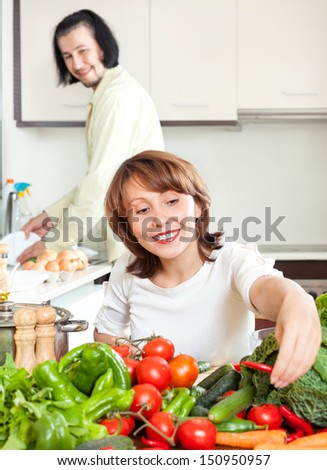 Young happy couple cutting the celery for salad in home kitchen