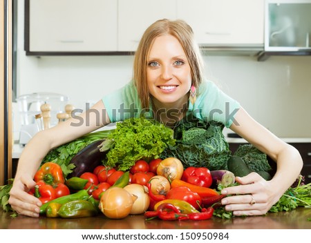 woman with heap of vegetables in kitchen