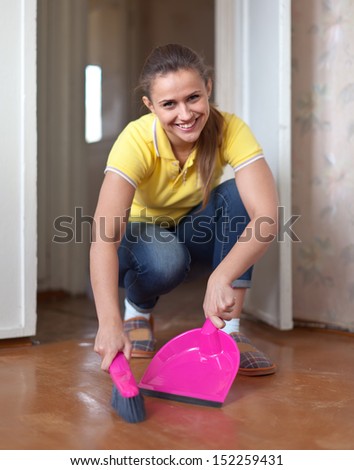 Girl sweeps the floor at home