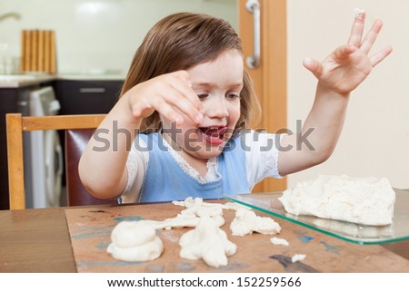 Cute little girl learning to sculpt dough figurines in the room