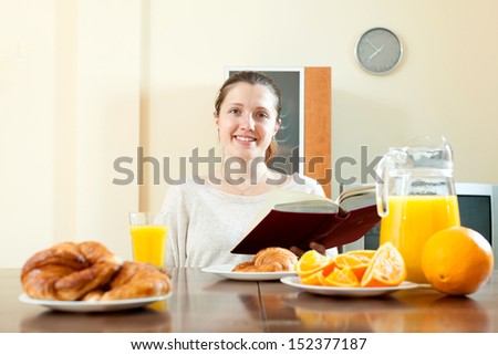 Positive brunette woman having breakfast with juice in morning